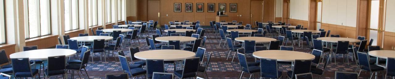 An interior view of the Loosemore Forum in the L.William Seidman Center staged with round tables and chairs, but otherwise empty